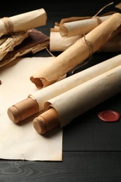 Photo of Many old rolled scrolls on black wooden table, closeup