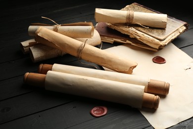 Photo of Many old rolled scrolls on black wooden table, closeup