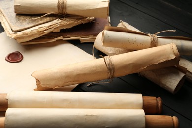 Photo of Many old rolled scrolls on black wooden table, closeup