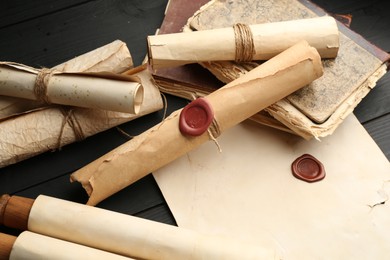 Photo of Many old rolled scrolls on black wooden table, closeup