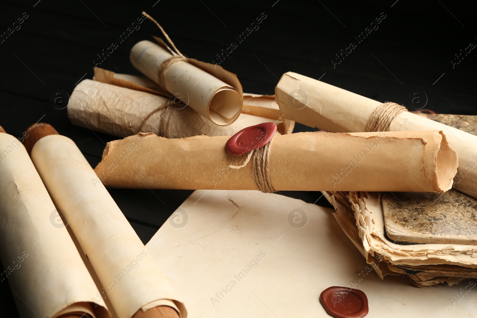 Many old rolled scrolls on black wooden table, closeup Photo of Many old rolled scrolls on black wooden table, closeup