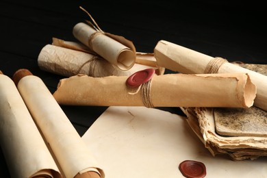 Photo of Many old rolled scrolls on black wooden table, closeup