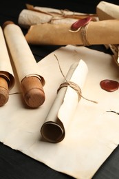 Photo of Many old rolled scrolls on black wooden table, closeup