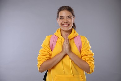 Photo of Excited student with clasped hands happy about her good exam result on gray background