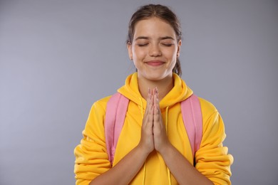 Photo of Student praying for good exam result on gray background