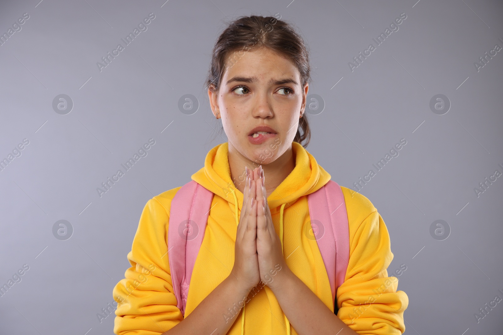 Student praying for good exam result on gray background Photo of Student praying for good exam result on gray background