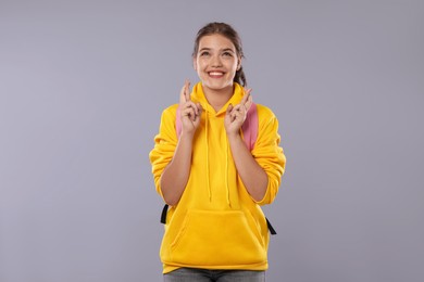 Photo of Excited student crossing fingers on gray background. Hope for good exam result