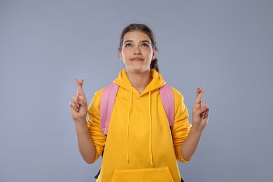 Photo of Student crossing fingers on gray background. Hope for good exam result