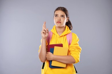Photo of Student crossing fingers on gray background. Hope for good exam result
