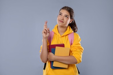 Photo of Student crossing fingers on gray background. Hope for good exam result
