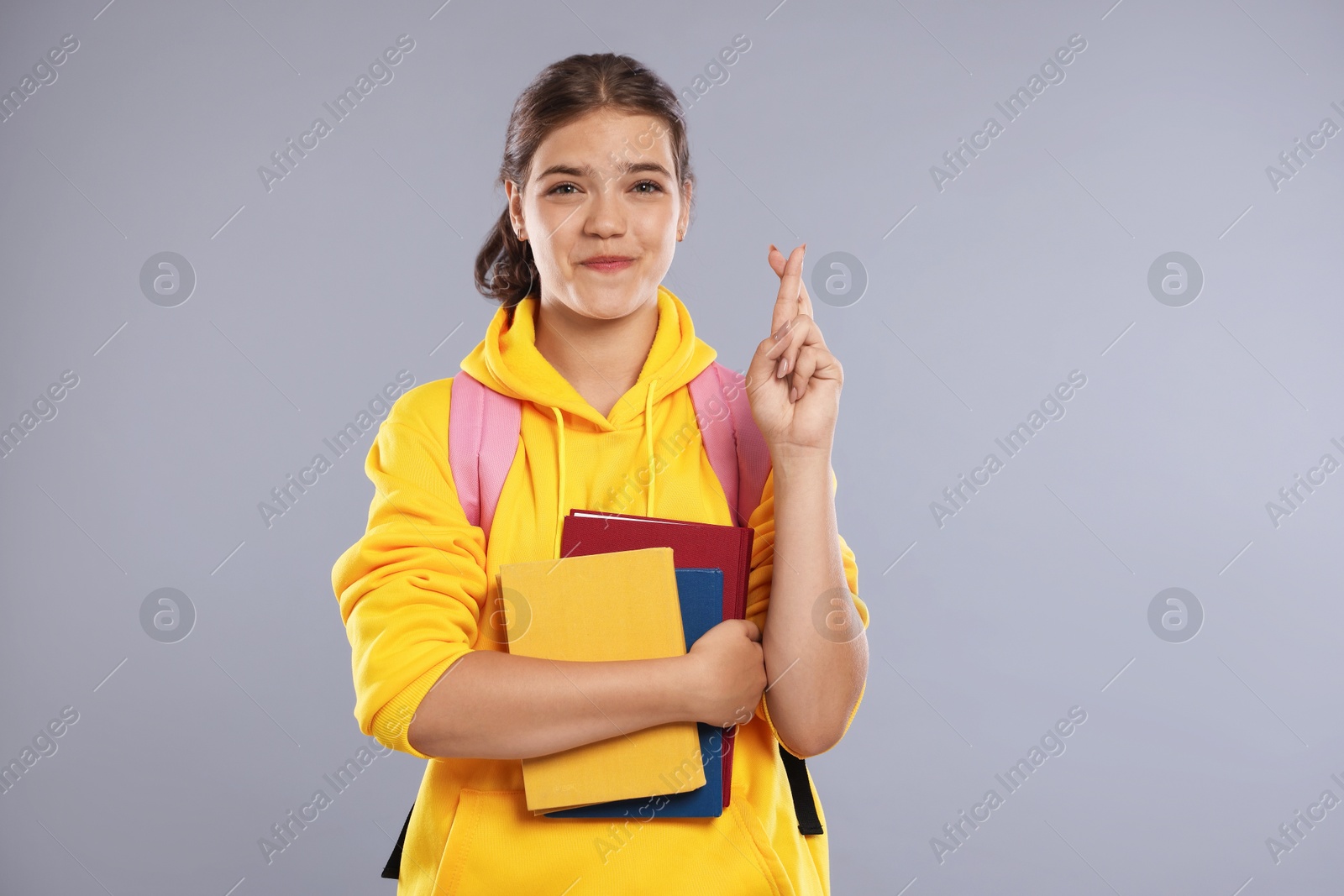Student crossing fingers on gray background. Hope for good exam result Photo of Student crossing fingers on gray background. Hope for good exam result