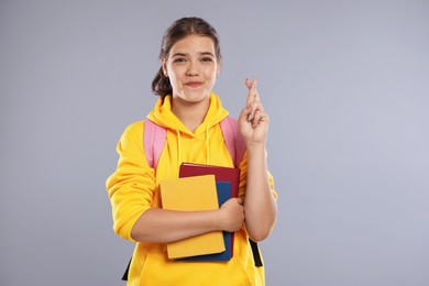 Photo of Student crossing fingers on gray background. Hope for good exam result