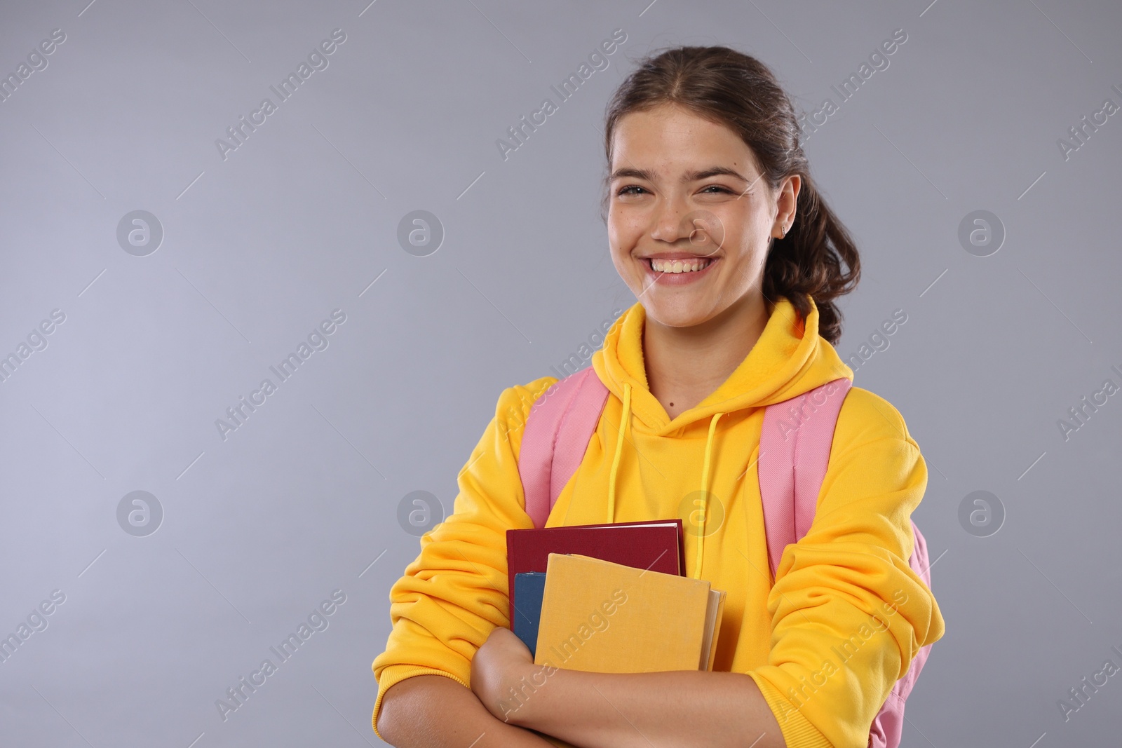 Student with notebooks happy about her good exam result on gray background Photo of Student with notebooks happy about her good exam result on gray background