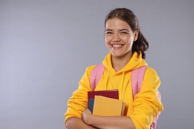 Photo of Student with notebooks happy about her good exam result on gray background