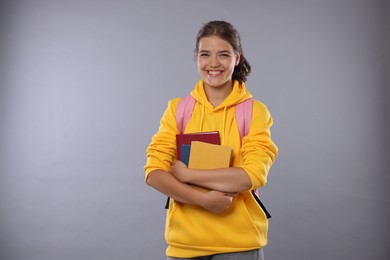 Photo of Student with notebooks happy about her good exam result on gray background