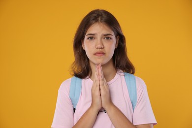 Photo of Student praying for good exam result on orange background