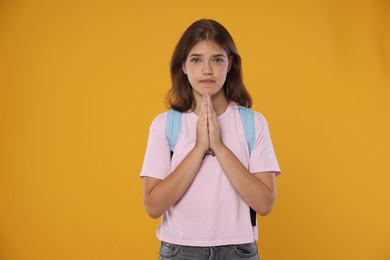 Photo of Student praying for good exam result on orange background