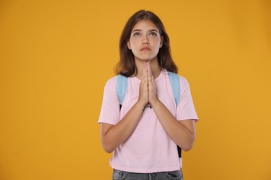 Photo of Student praying for good exam result on orange background