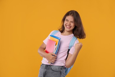 Photo of Student feeling happy about her good exam result on orange background