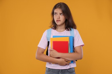 Photo of Student with notebooks worried about her exam result on orange background