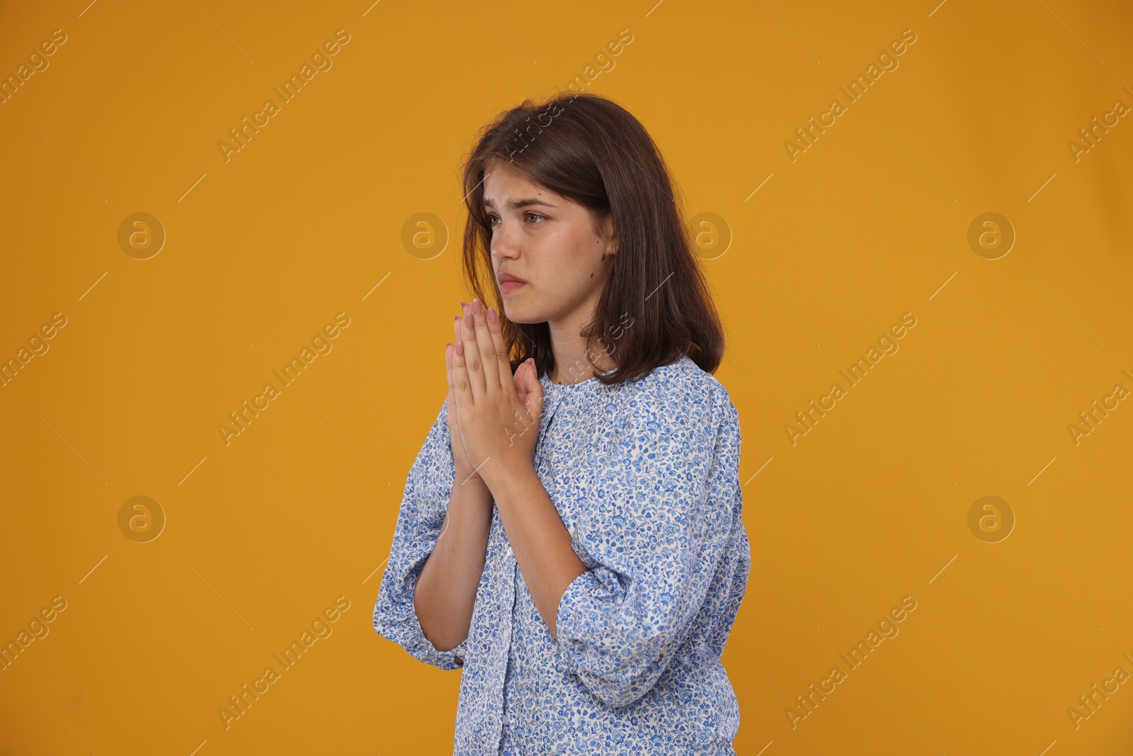 Student praying for good exam result on orange background Photo of Student praying for good exam result on orange background