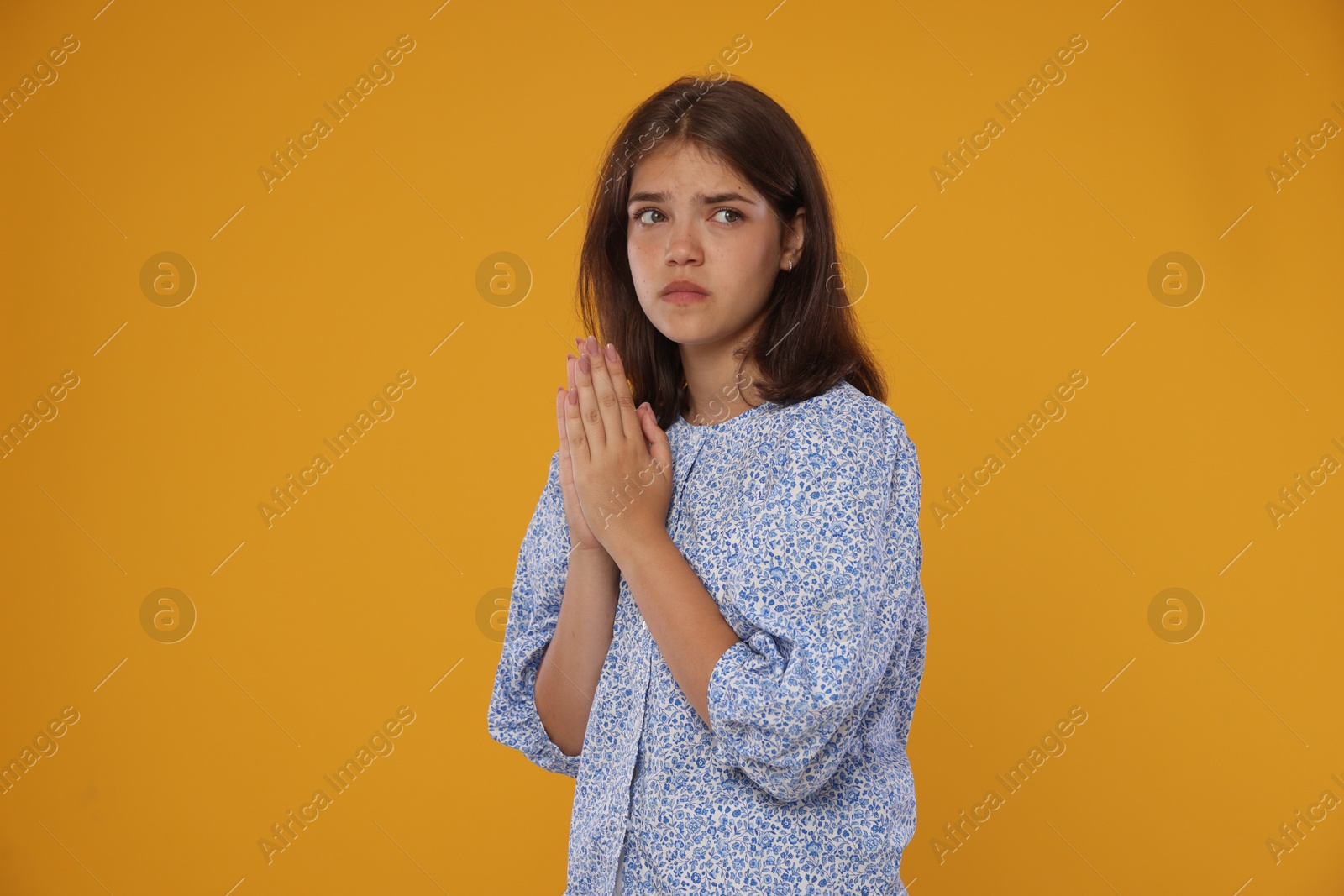 Student praying for good exam result on orange background Photo of Student praying for good exam result on orange background