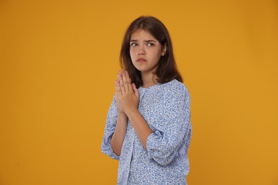 Photo of Student praying for good exam result on orange background
