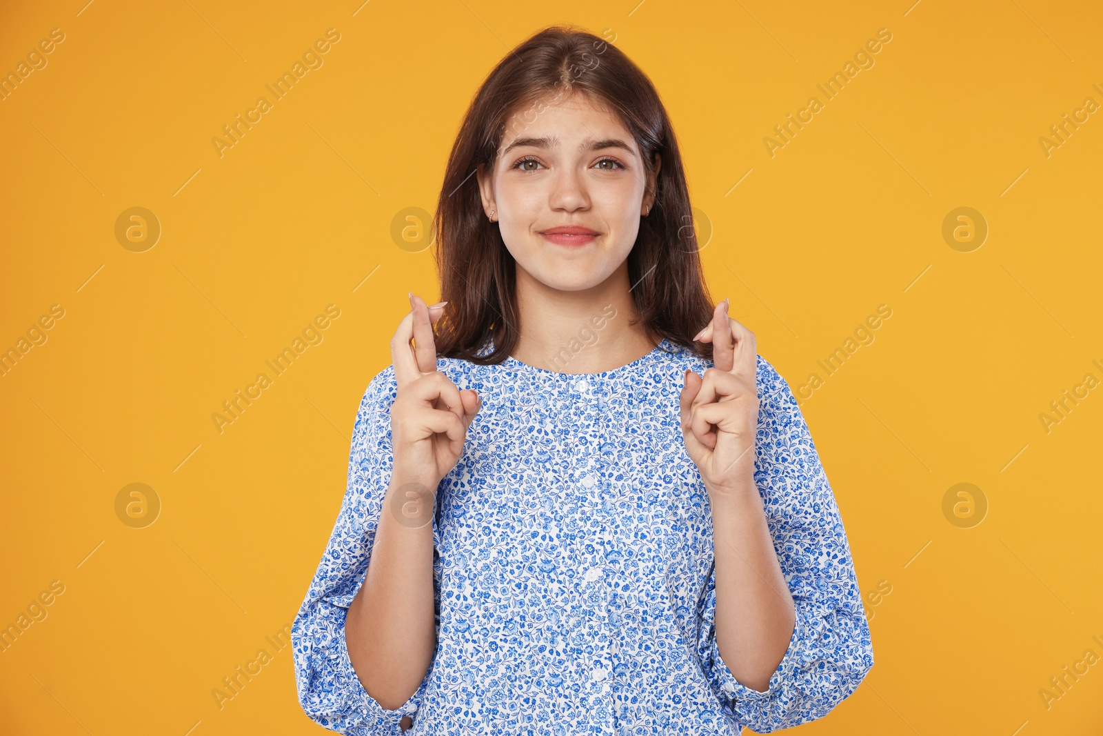 Student crossing fingers on orange background. Hope for good exam result Photo of Student crossing fingers on orange background. Hope for good exam result
