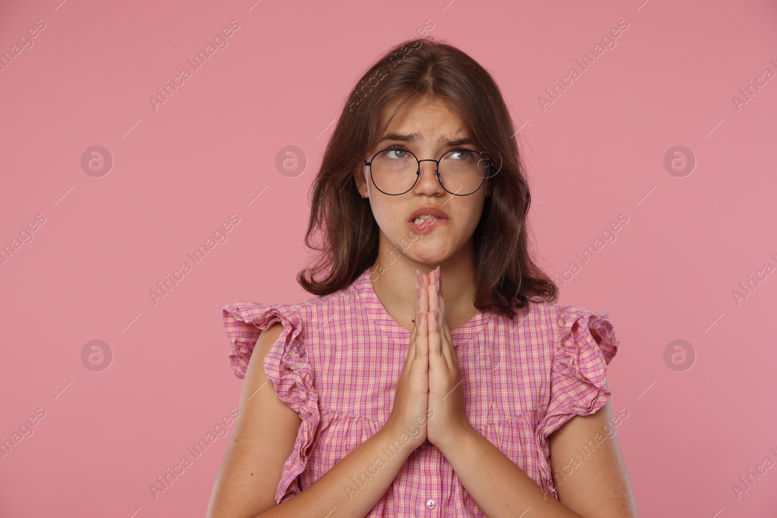 Student praying for good exam result on pink background Photo of Student praying for good exam result on pink background