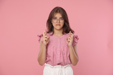 Photo of Student crossing fingers on pink background. Hope for good exam result