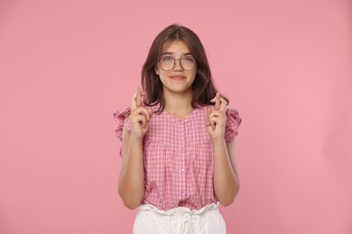 Photo of Student crossing fingers on pink background. Hope for good exam result