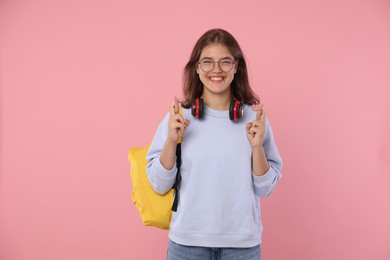 Photo of Student crossing fingers on pink background. Hope for good exam result