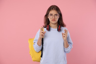 Photo of Student crossing fingers on pink background. Hope for good exam result