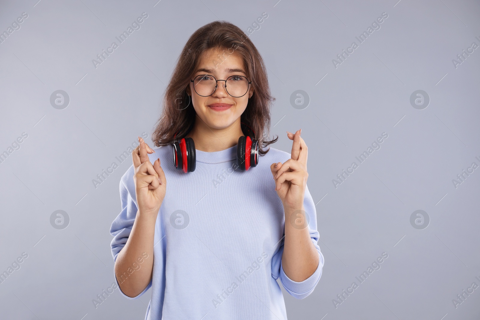 Student crossing fingers on gray background. Hope for good exam result Photo of Student crossing fingers on gray background. Hope for good exam result