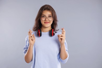 Photo of Student crossing fingers on gray background. Hope for good exam result