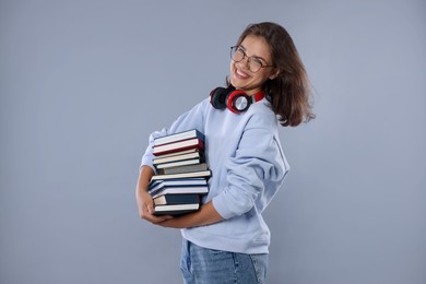 Photo of Student with stack of books feeling happy about her good exam result on gray background