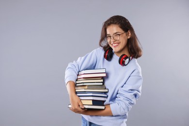 Photo of Student with stack of books feeling happy about her good exam result on gray background