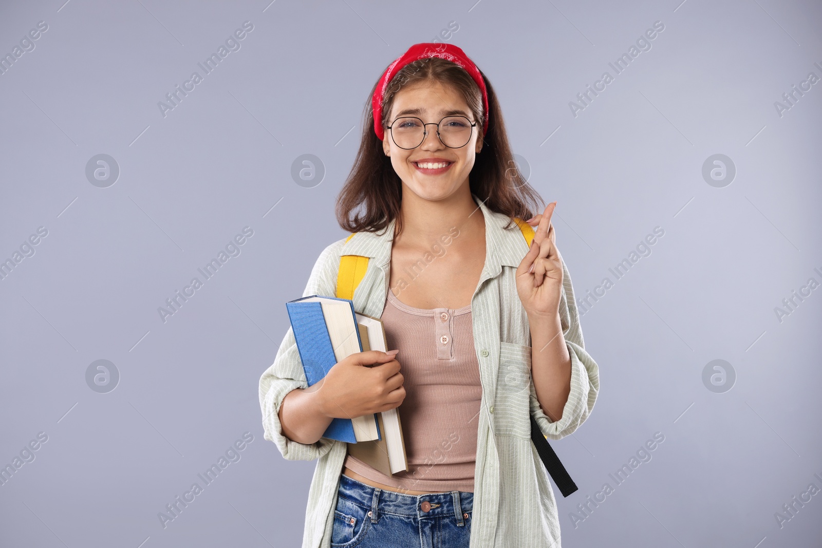 Student crossing fingers on gray background. Hope for good exam result Photo of Student crossing fingers on gray background. Hope for good exam result