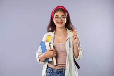 Photo of Student crossing fingers on gray background. Hope for good exam result