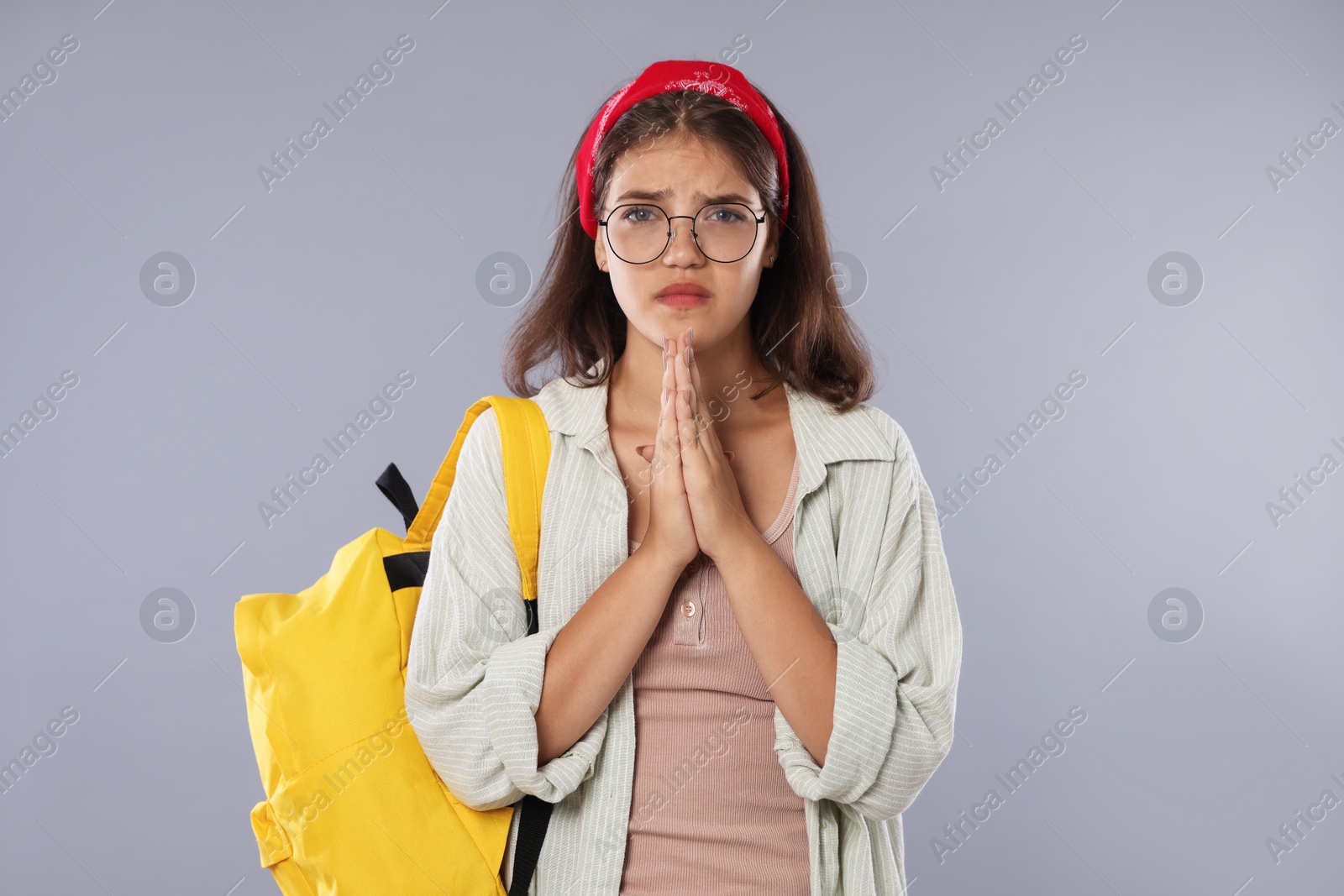 Student praying for good exam result on gray background Photo of Student praying for good exam result on gray background