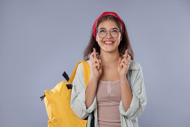 Photo of Excited student crossing fingers on gray background. Hope for good exam result