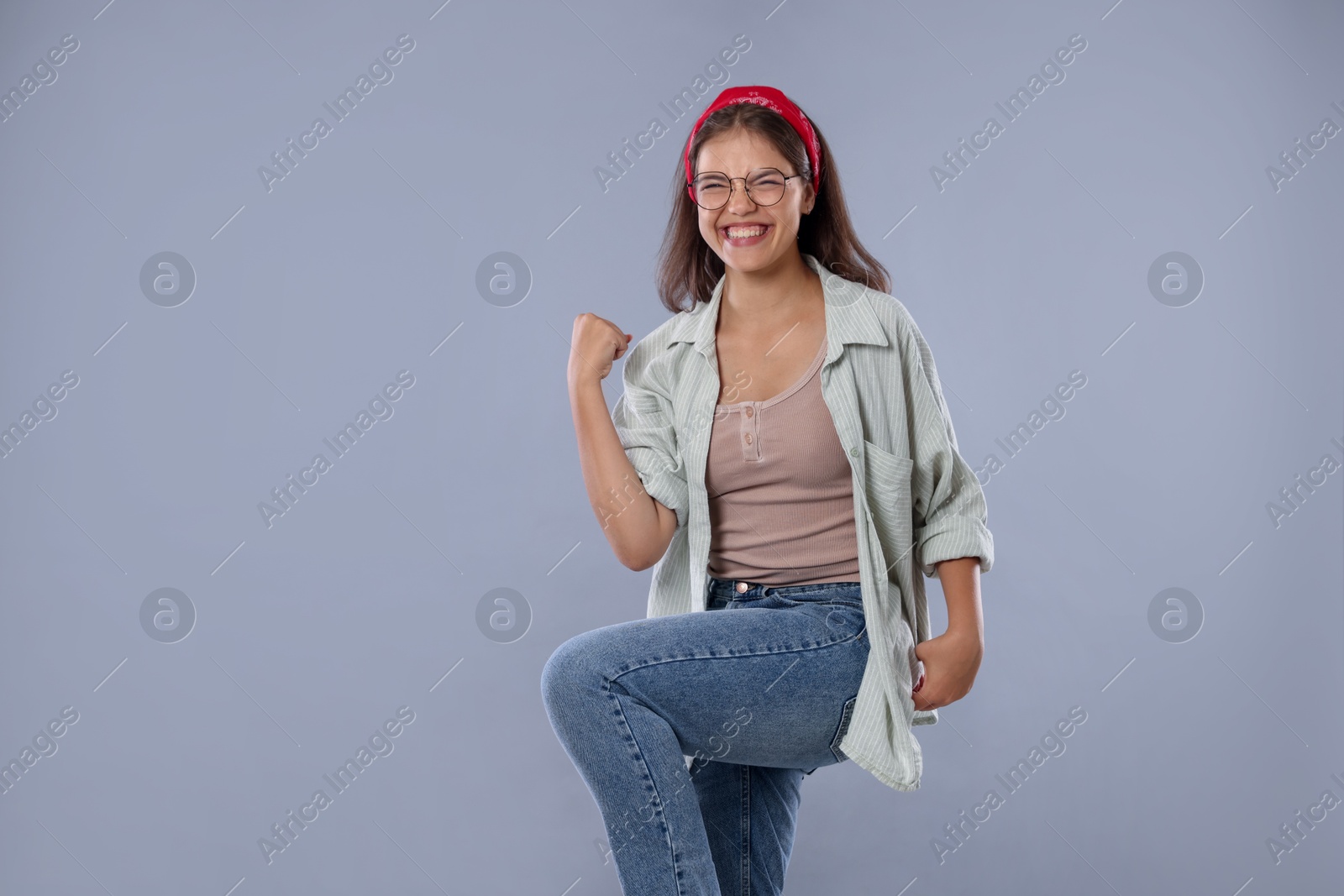 Student feeling happy about her good exam result on gray background Photo of Student feeling happy about her good exam result on gray background