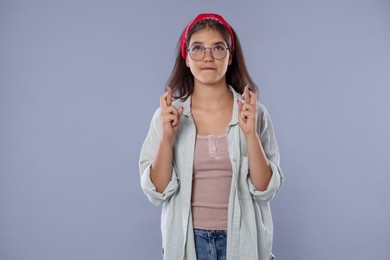 Photo of Student crossing fingers on gray background. Hope for good exam result