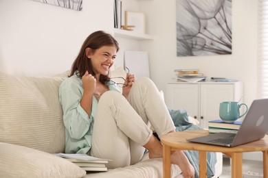 Photo of Student feeling happy about her good exam result at wooden table with laptop indoors