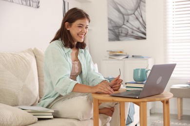 Photo of Student feeling happy about her good exam result at wooden table with laptop indoors