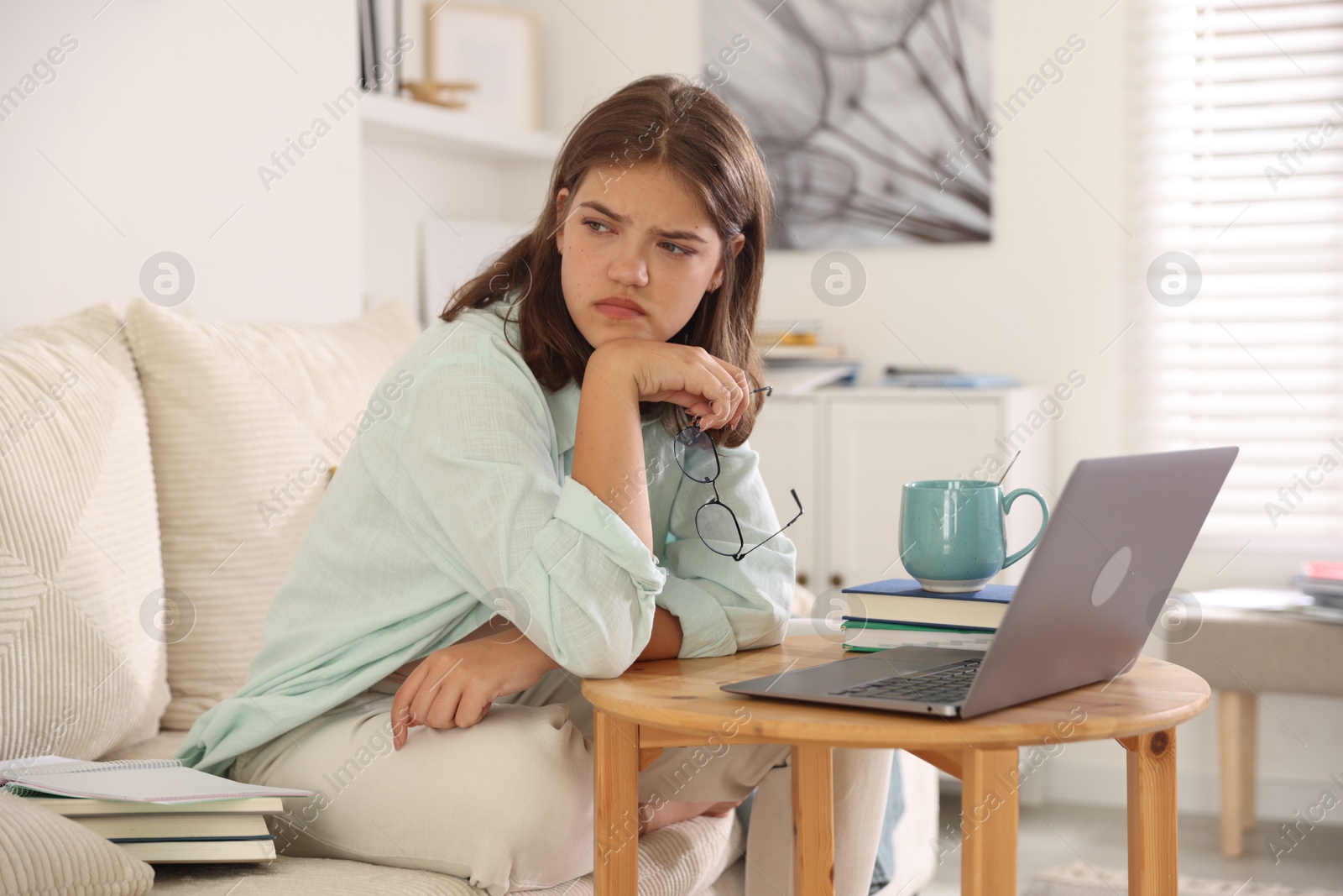 Student feeling unhappy about her exam result at wooden table with laptop indoors Photo of Student feeling unhappy about her exam result at wooden table with laptop indoors