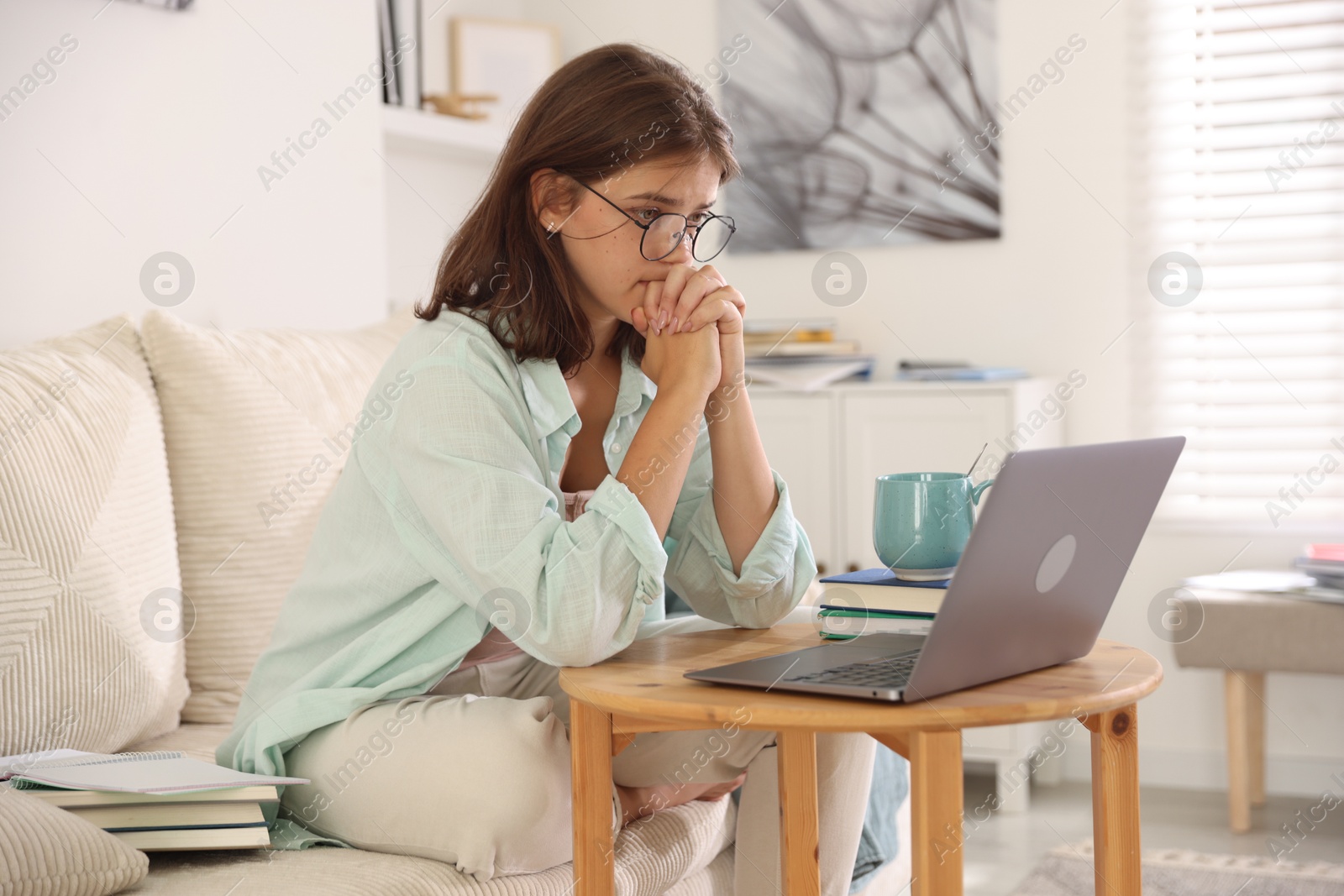Student feeling unhappy about her exam result at wooden table with laptop indoors Photo of Student feeling unhappy about her exam result at wooden table with laptop indoors