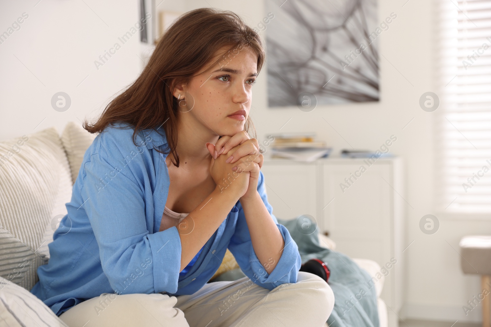 Student praying for good exam result on sofa indoors Photo of Student praying for good exam result on sofa indoors