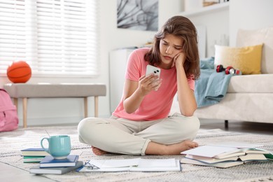 Photo of Student with smartphone feeling unhappy about her exam result at home