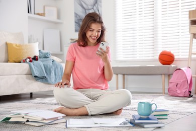Photo of Student with smartphone feeling happy about her good exam result at home